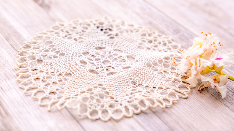 A vintage lace doily on a table with dried flowers