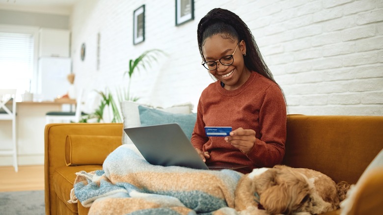 Smiling woman sitting on couch while shopping online