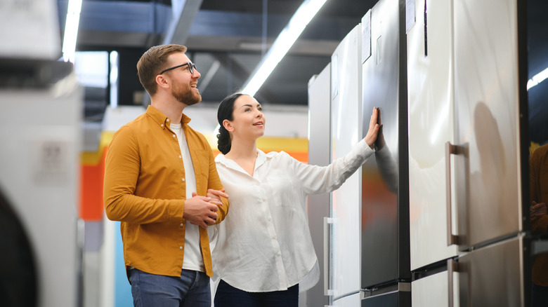 A couple shopping for refrigerators in an appliance store.