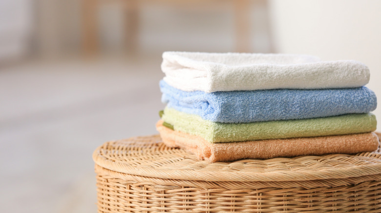 Stack of small folded towels on a basket with a lid.