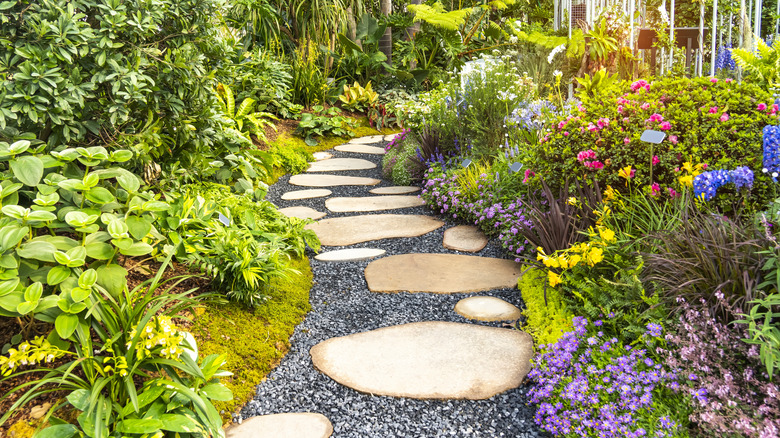 A gravel and flagstone path winding through a flowery garden border.