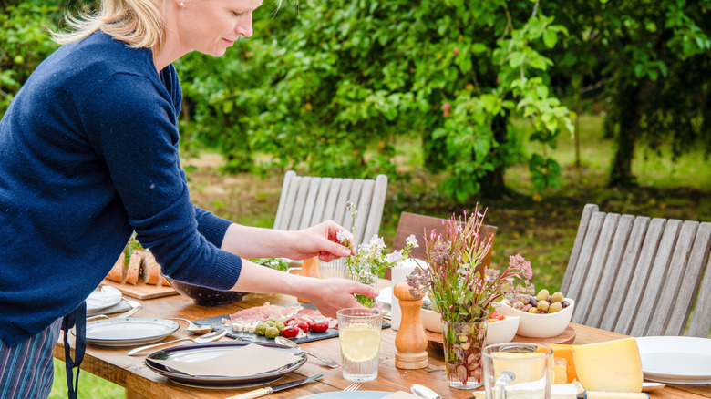 A person setting up an outdoor table for hosting