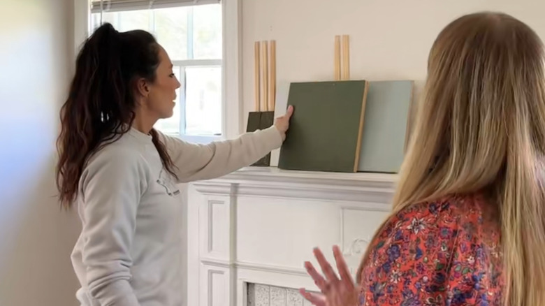 Joanna Gaines puts green paint samples against a white fireplace