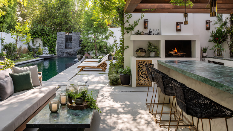 A Mediterranean backyard with a pool, seating area, outdoor bar, and fireplace