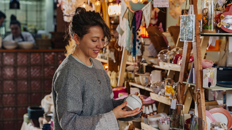 a woman shopping for vintage trinkets and decor at cluttered thrift store
