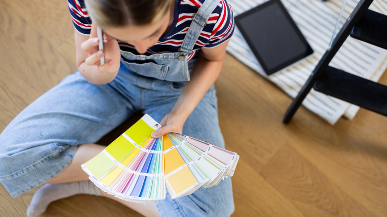 Woman sitting on the floor, looking at paint color samples while on the phone