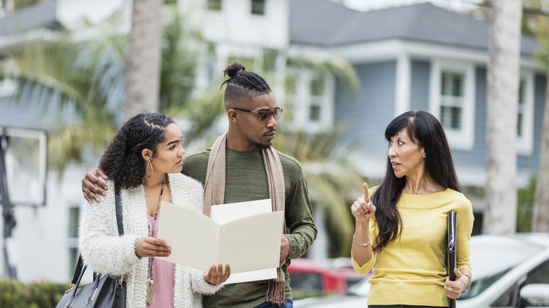 Real estate agent showing a couple homes for sale with palm trees in the background