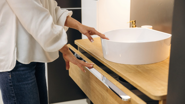 Woman opening drawer of bathroom vanity