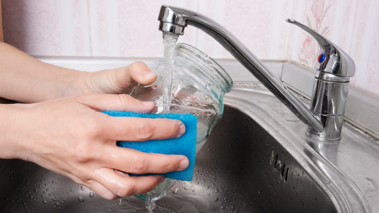 Woman cleaning an empty pickle jar