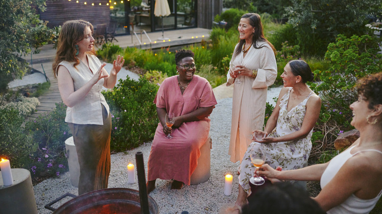 A group of women enjoy their outdoor patio space in a beautifully landscaped backyard.