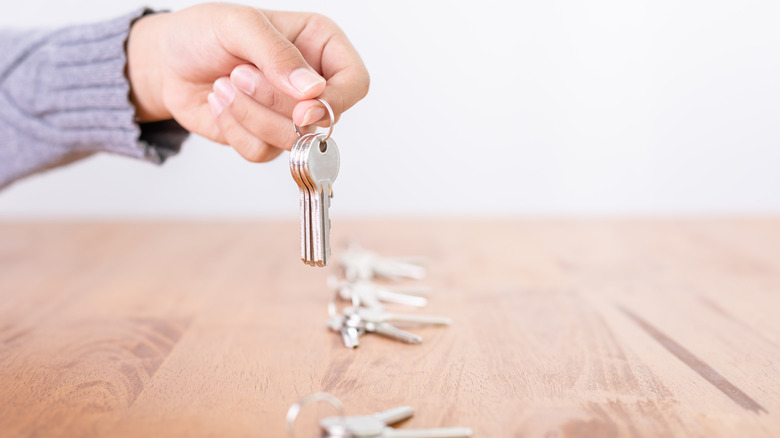 Hands picking up keys on kitchen table