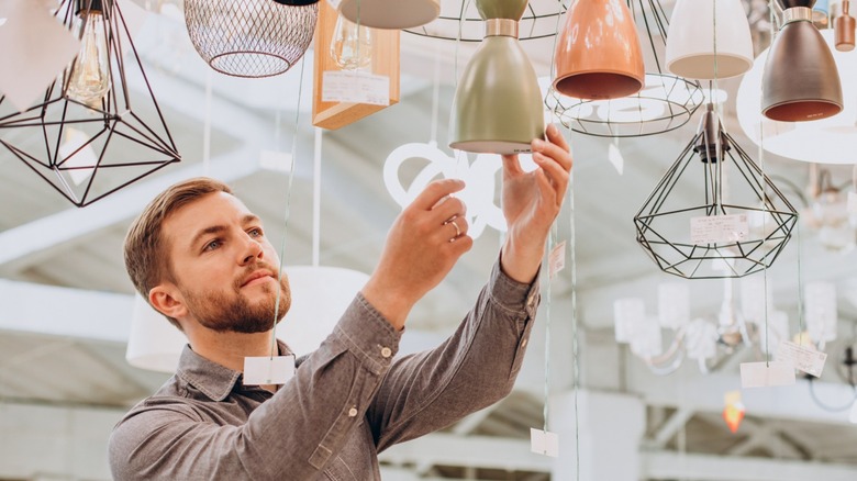 Man looking at overhead lighting options in a thrift store
