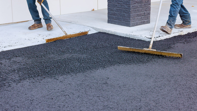 workers leveling a fresh asphalt driveway
