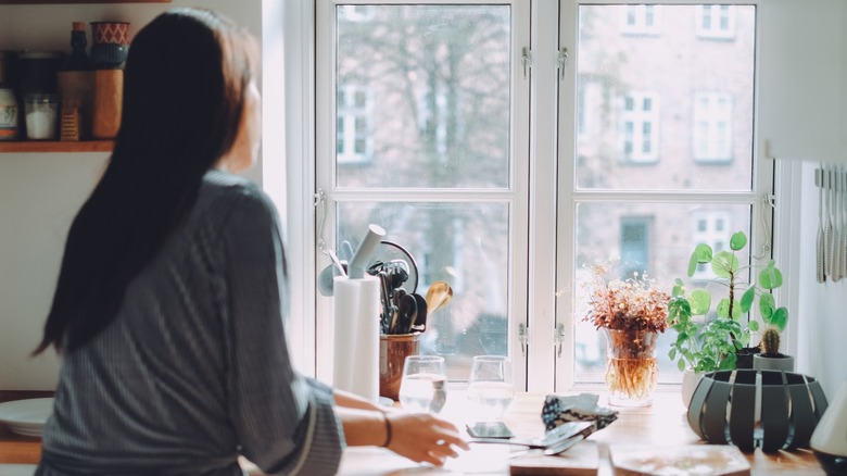 Person looking out the kitchen window on a bright day