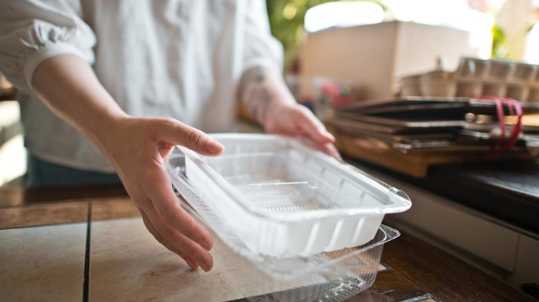 Man reaching for empty and clean plastic takeout container in outdoor kitchen