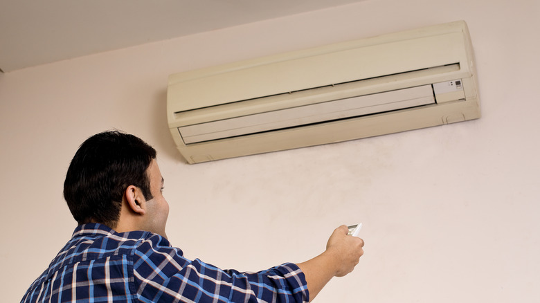 A man switching on an air conditioner.