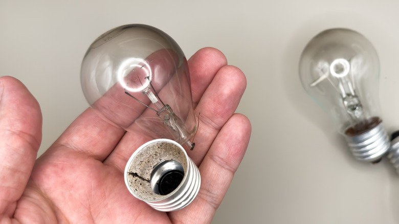 Hand holding a light bulb that has been separated from its base