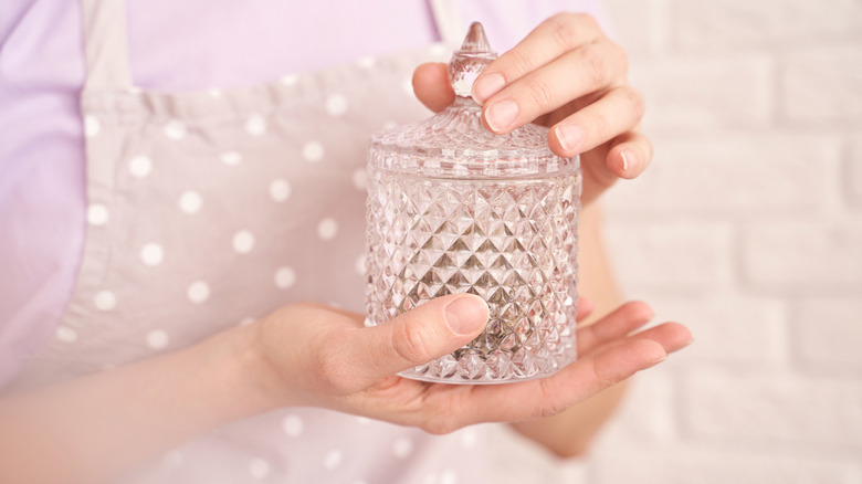 Woman in polka-dot apron holding crystal candy jar