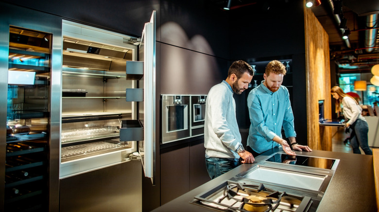 A shopper checks out a stovetop in a high-end appliance store.
