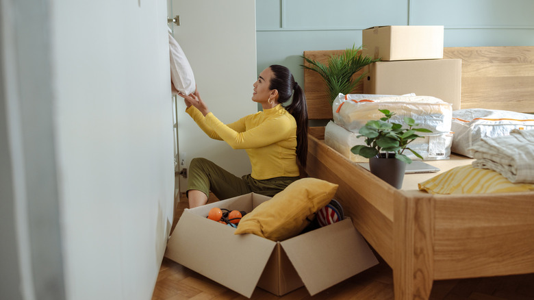 Woman putting items into a box as she declutters her wardrobe