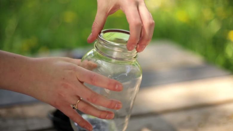 Hand opening pickle jar in outdoor setting
