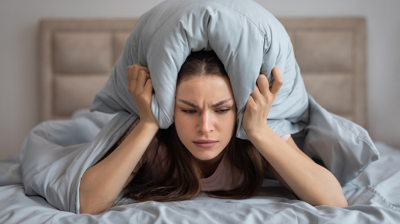 Frustrated woman trying to block noise with a pillow