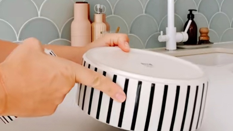 A woman prepares a striped IKEA pet bowl for a DIY project