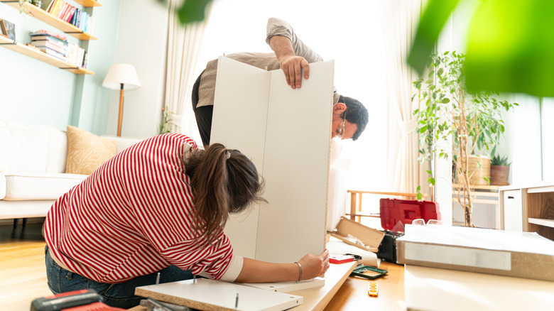 A young couple tries to assemble a piece of IKEA furniture