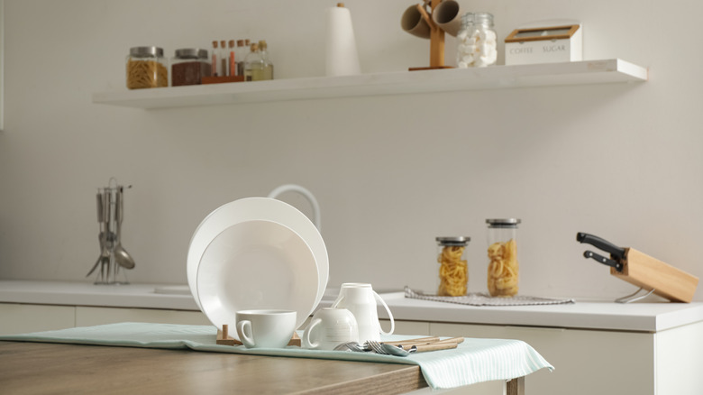 Plates, spice bowls, and other kitchen clutter on wood countertop