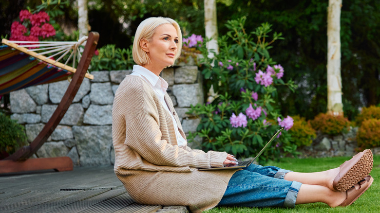 A woman sits in her yard, contemplating