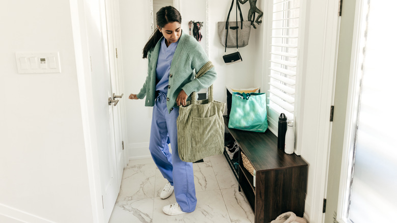 A woman walks into a small cluttered entryway