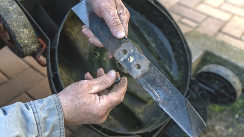 Homeowner looking at beaten up mower blade