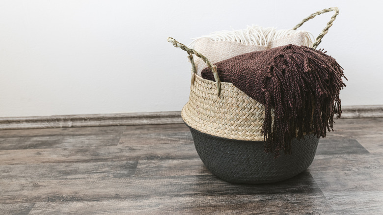 Blankets in a basket on a grey-colored wooden floor