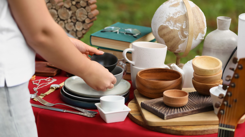 A person picks up plates and bowls at a flea market