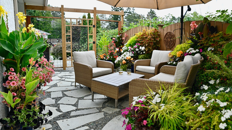 A patio with plants, wicker furniture, and flagstone floors
