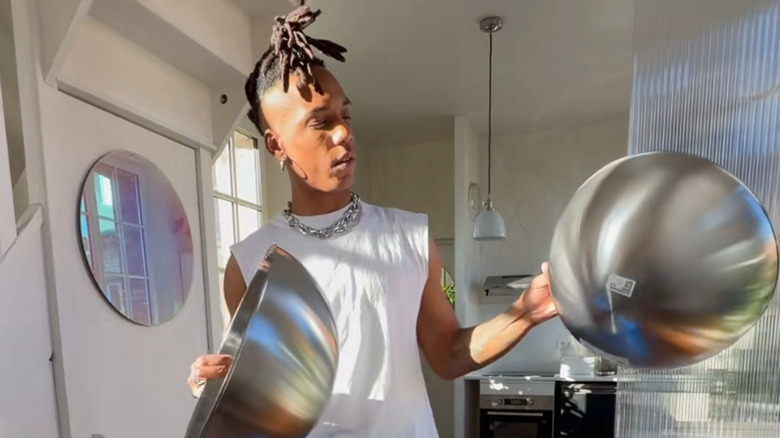 Person holding two large metal IKEA salad bowls