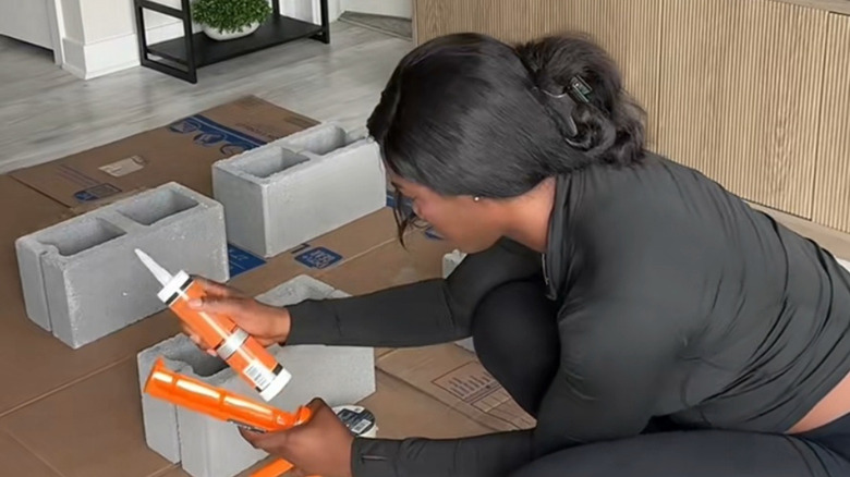 Woman putting preparing to add hot glue to cinder blocks