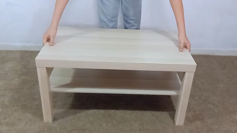 A person prepares an IKEA Lack coffee table