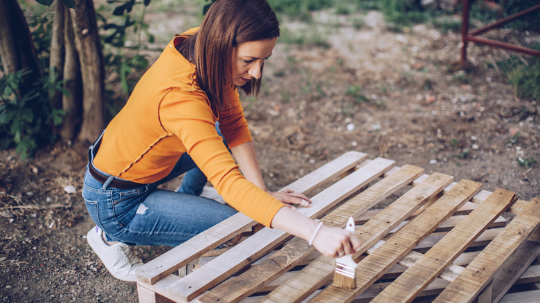 Woman painting stain on wood pallet