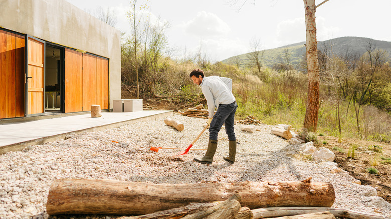 A man preparing to dig his garden covered in gravel