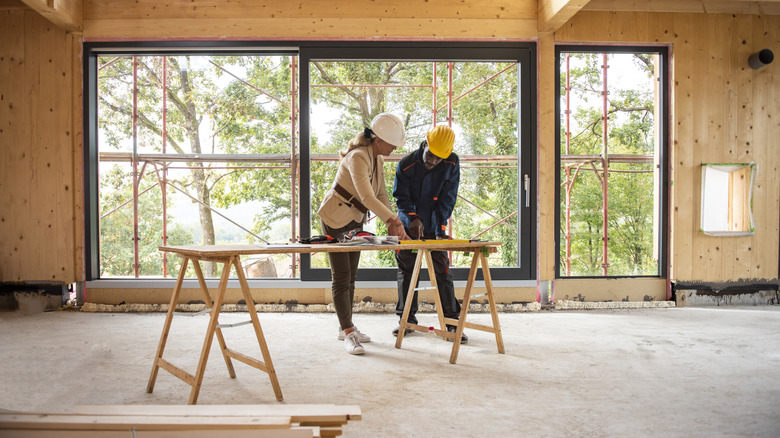 A woman and architect stand at a worktable inside a framed home