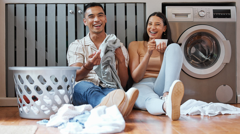 Young couple sitting on the floor doing laundry