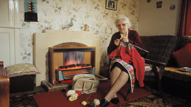 An elderly woman knitting in an old-fashioned quaint living room