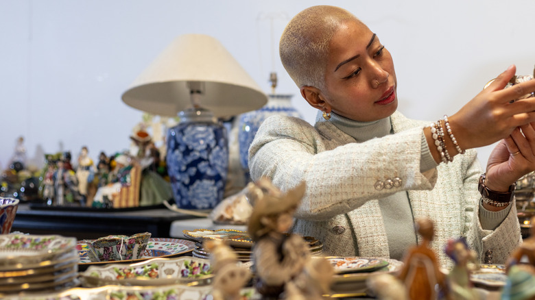 Woman looking at porcelain decor in thrift shop