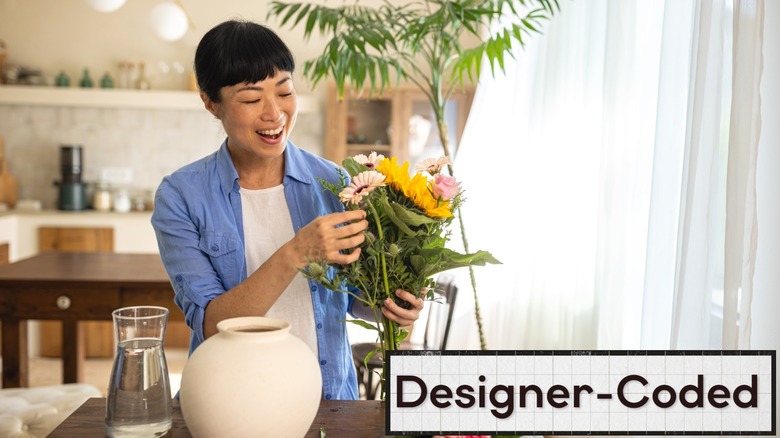 Smiling person choosing flowers to put into round vase