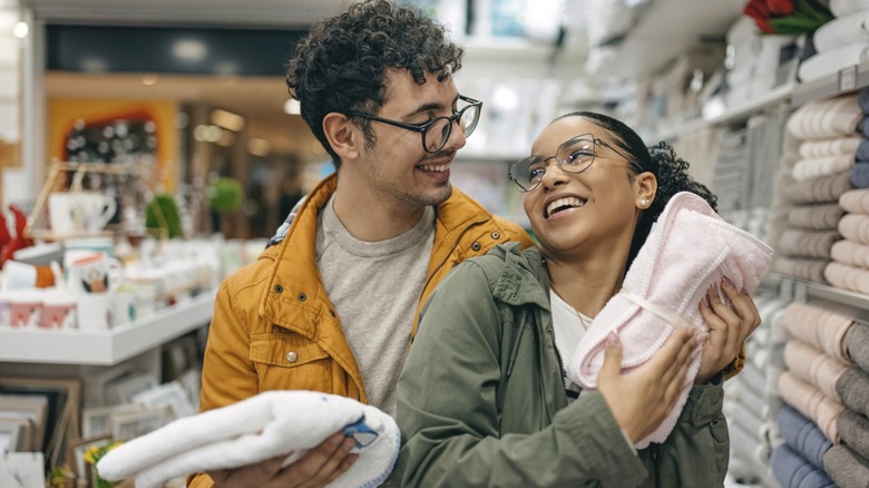A smiling couple testing different towels in a store