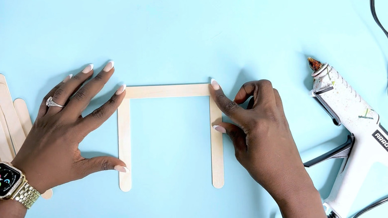 hands gluing popsicle sticks