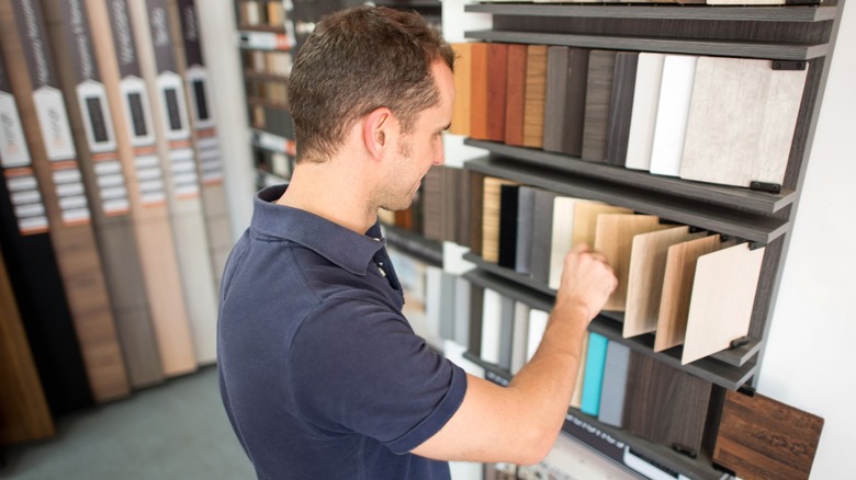 Man flipping through different wood floor samples in home improvement store