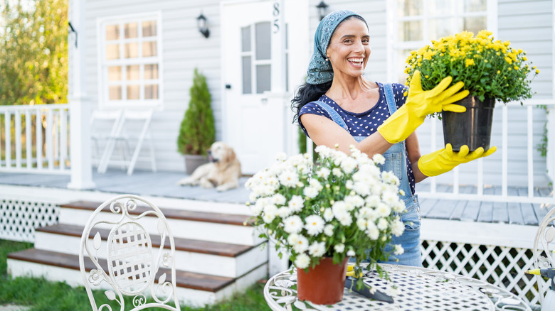 Woman holding potted flowers in front of her porch