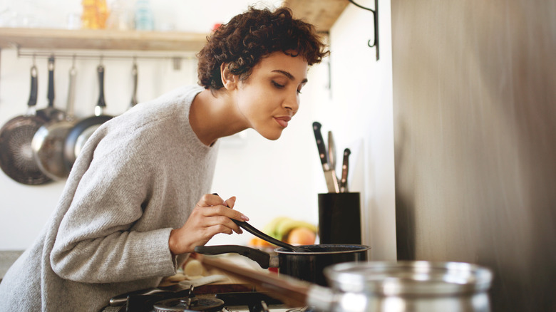 A person leans over the stove while cooking